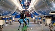 Der Roboterhund steht zwischen Wassertanks im Kraftwerk.