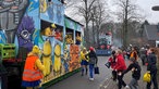 Ein Karnevalswagen mit Kindern am Straßenrand.