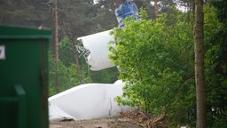 Trümmerteile eines Windrads liegen auf einem Waldboden.