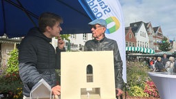 Zwei Männer stehen hinter einem kleinen gebauten Kirchenmodell in Oelde.