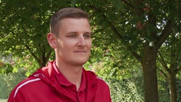 Ein Portraitfoto von Schwimmeister Fabian Burde zwischen Bäumen im Freibad