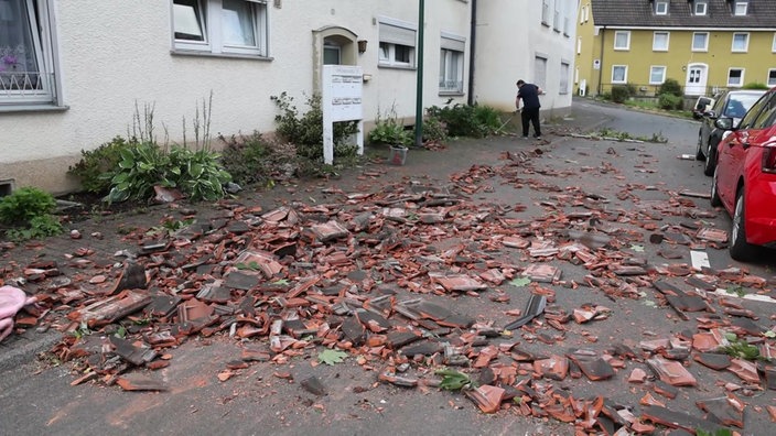 Vor einem Wohnhaus liegen zahlreiche Dachziegel.