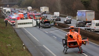 Große Sperrung auf der A33 wegen Unfall. Vorne steht ein Helikopter auf der Fahrbahn und Rettungswagen und Menschen im Hintergrund.