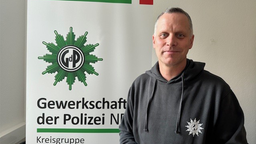 Björn Lüdtke steht vor Banner der Gewerkschaft der Polizei.