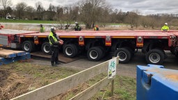 Arbeiter dirigieren einen Schwerlast-Transporter