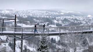 Spaziergänger gehen über den Skywalk neben der Bobbahn in Winterberg