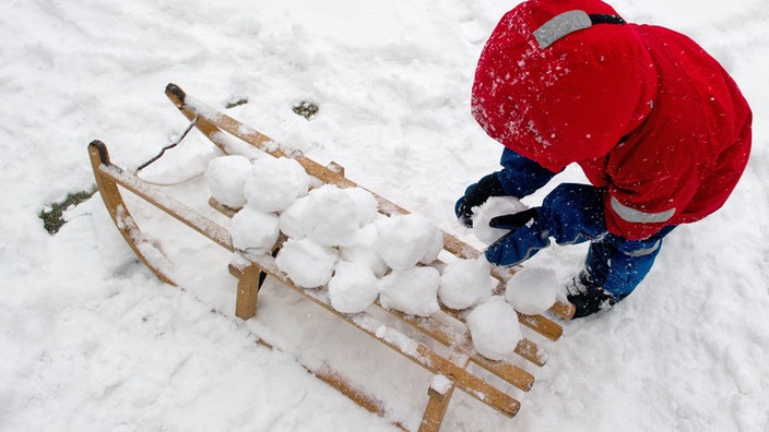 Kind stapelt Schneebälle