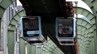 Die Schwebebahn in Wuppertal fährt in der Nacht über eine Straße hinweg.