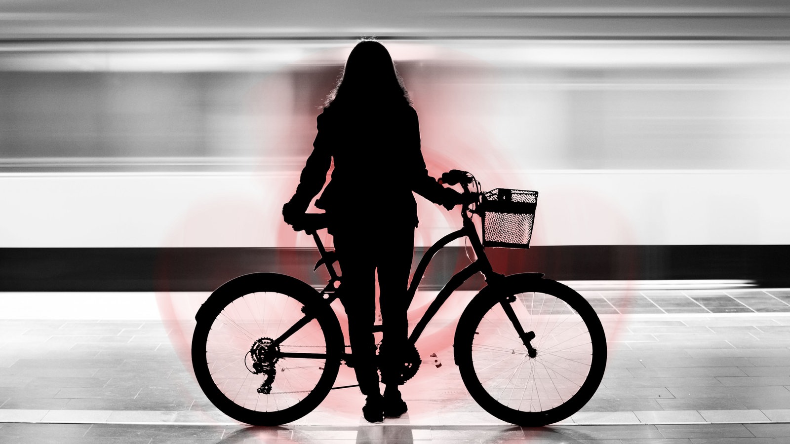 Eine Frau steht mit ihrem Fahrrad an einer U-Bahn-Haltestelle.