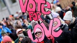 Demonstrantin mit Schild "Vote für Love" 