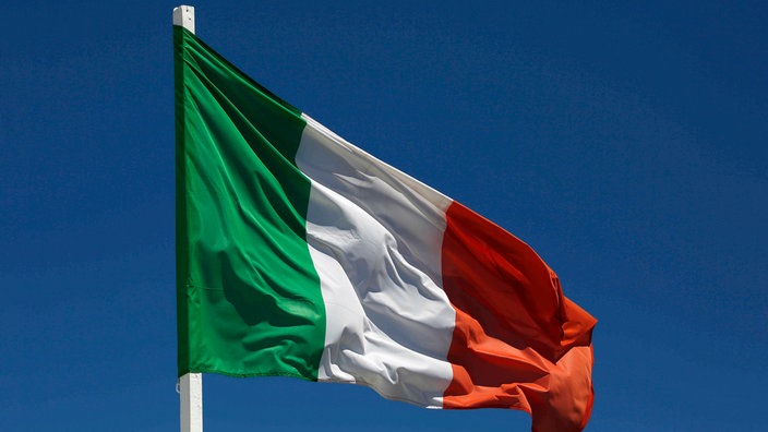 Die italienische Flagge weht gegen einen hellblauen Himmel