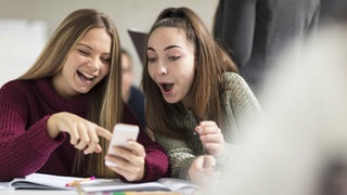 Zwei Mädchen schauen auf das Handy und lachen