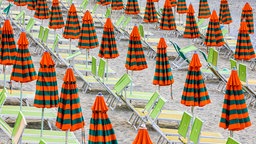 Una spiaggia con gli ombrelloni chiusi