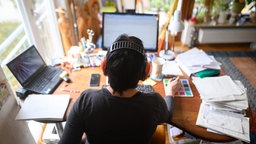 Mann sitzt vor einem Computer am Schreibtisch