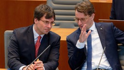 Marcus Optendrenk, Finanzminister des Landes Nordrhein-Westfalen (l, CDU), und Hendrik Wüst, Ministerpräsident von NRW (r) beraten sich im Landtag von Nordrhein-Westfalen 