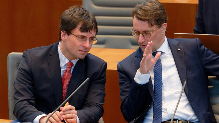 Marcus Optendrenk, Finanzminister des Landes Nordrhein-Westfalen (l, CDU), und Hendrik Wüst, Ministerpräsident von NRW (r) beraten sich im Landtag von Nordrhein-Westfalen 