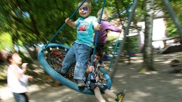 Schaukelnde Kinder auf einem Spielplatz