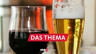 Ein Glas Wein und ein Glas Bier stehen in einem Café auf einem Tablett, das auf einem Tisch steht