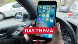 Eine Hand am Smartphone, die andere am Lenkrad des Fahrzeuges