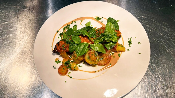 Gefüllte Zucchini mit Bratkartoffeln, angerichtet auf einem Teller