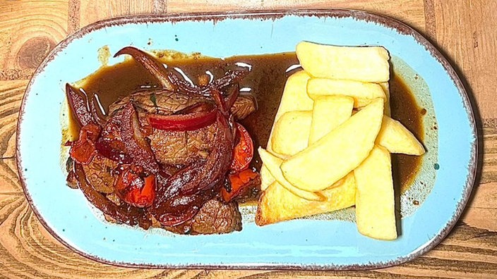 Lomo Saltado mit Kartoffeln, angerichtet auf einem Teller