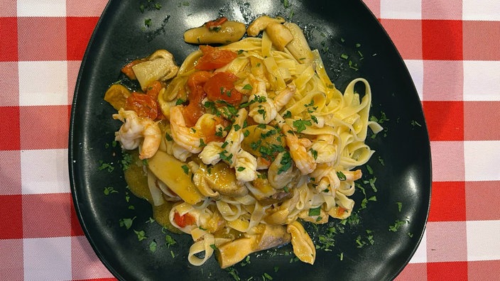 Tagliatelle mit Steinpilzen und Gambas, angerichtet auf einem Teller