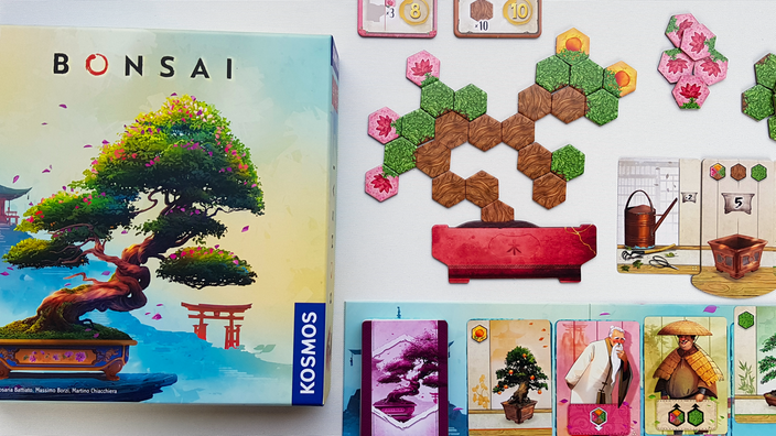 Die Spielschachtel von "Bonsai" zeigt einen Miniaturbaum in einer Schale, daneben ein Baum aus sechseckigen Spielplättchen, und eine Kartenauslage