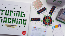 Die Spieleschachtel von Turing Machine liegt neben dem Spielmaterial, das aus Lochkarten, Testkarten und Antwortkarten mit Häkchen und Kreuzen besteht