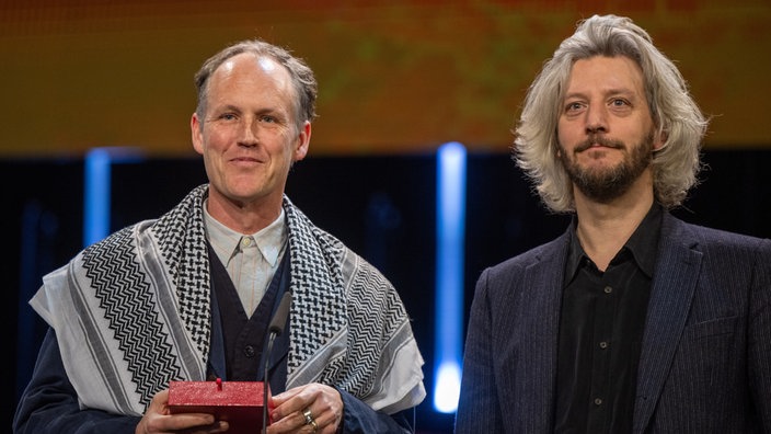 Ben Russell (l) und Guillaume Cailleau und stehen während der Preisverleihung bei der Abschlussgala im Berlinale Palast auf der Bühne.