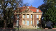 Außenansicht des Gebäudes mit Treppe und Eingang vor blauem Himmel