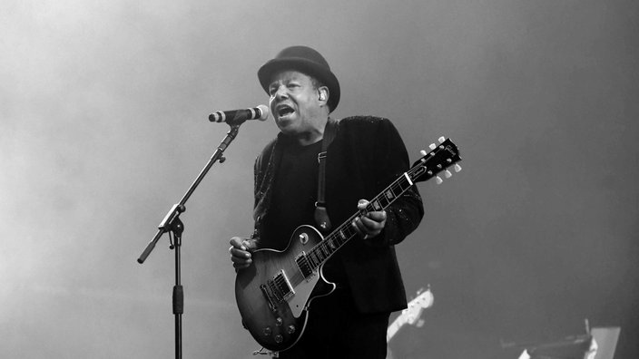 Schwarz-Weiß-Aufnahme von Tito Jackson mit Gitarre auf der Bühne am 18. August 2024.