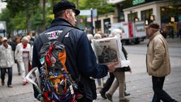 Ein ehemaliger Obdachloser verkauft  vor einem Kaufhaus in Hamburg das Straßenmagazin "Hinz & Kunzt". 