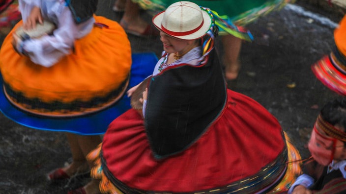 Frauen drehen sich in bunten Kleidern in Cuenca, Ecuador.