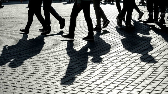 Schatten von Passanten die über eine Straße laufen.