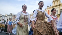 Auf dem Marktplatz in Krakau tanzen hunderte Menschen eine Polonaise 