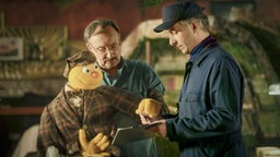 ie Handpuppe Spencer und Puppenspieler Jakob Sesam (Rainer Bock, M) unterschreiben den Lieferschein eines Lieferanten (Jan Böhmermann) in einer Szene des Films "Hallo Spencer - Der Film".