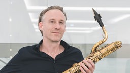 Porträtaufnahme vom Jazz-Musiker Marcus Bartelt mit einem Saxofon in der Hand.