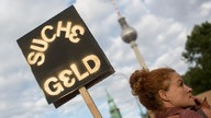 "Suche Geld" steht am 28.09.2013 auf dem Schild einer Demonstrantin in Berlin, während im Hintergrund der Fernsehturm zu sehen ist.