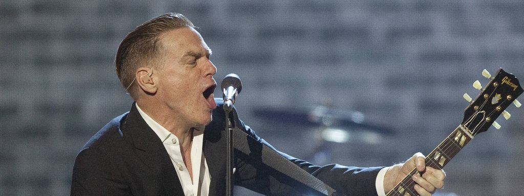 Bryan Adams singt und spielt Gitarre auf der Bühne