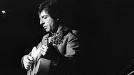 Leonard Cohen mit einer Gitarre um 1974