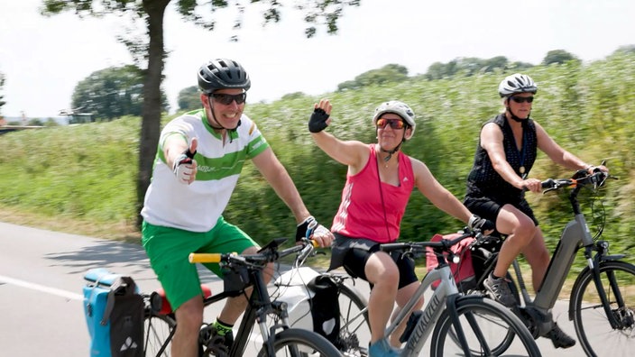 Drei Radfahrer bei der NRW winken in die Kamera