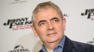 Rowan Atkinson 2018 im Hotel "The Fontenay" vor einer Wand, die den Schriftzug seines Films "Johnny English - Man lebt nur dreimal" trägt