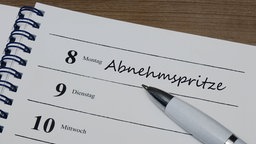 In einem Kalender befindet sich der Eintrag Abnehmspritze mit einem Kugelschreiber.