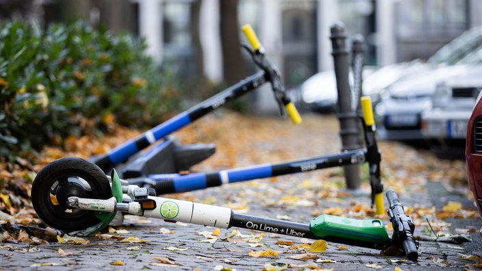 E-Scooter liegen auf einem Gehweg und versperren den Weg.