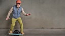 Modischer älterer Herr auf einem "One-wheeled electric skateboard"