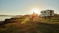 Ein Camper mit Wohnmobil bei Sonnenuntergang.