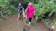 Zwei Frauen stehen in einem Bach