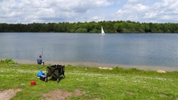 Ein Mann sitzt an einem See und angelt.