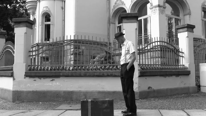 Marco Helbig alias "Der Reimteufel" im Musikvideo "Stolpersteine"  (SW-Sequenz mit Koffer)