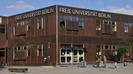 freie Universität Berlin, in rostbraunem Farbton, Hauptgebäude, davor gehen Menschen